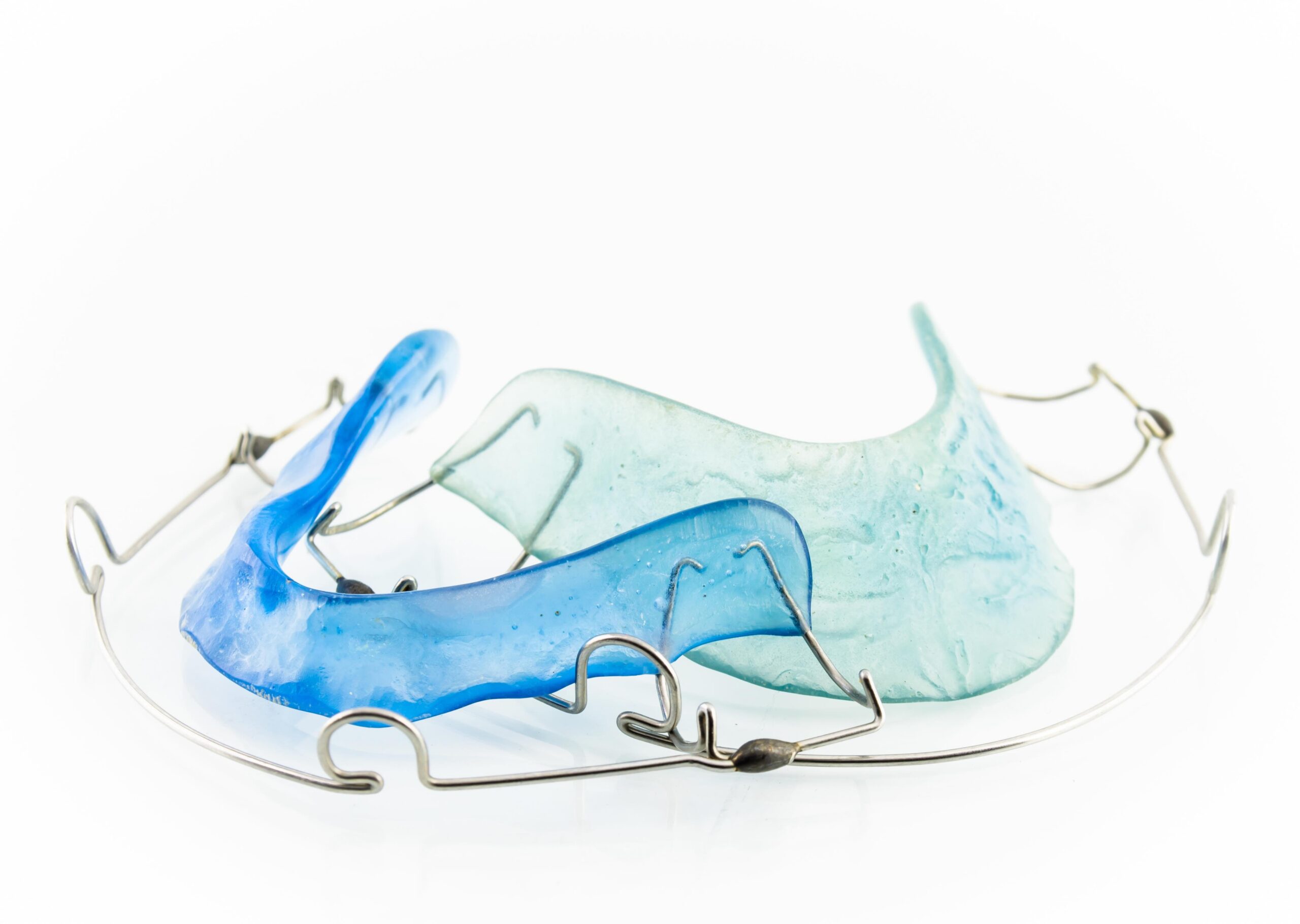 Two transparent plastic retainers with metal wires, one blue and one light green, arranged closely on a white background.