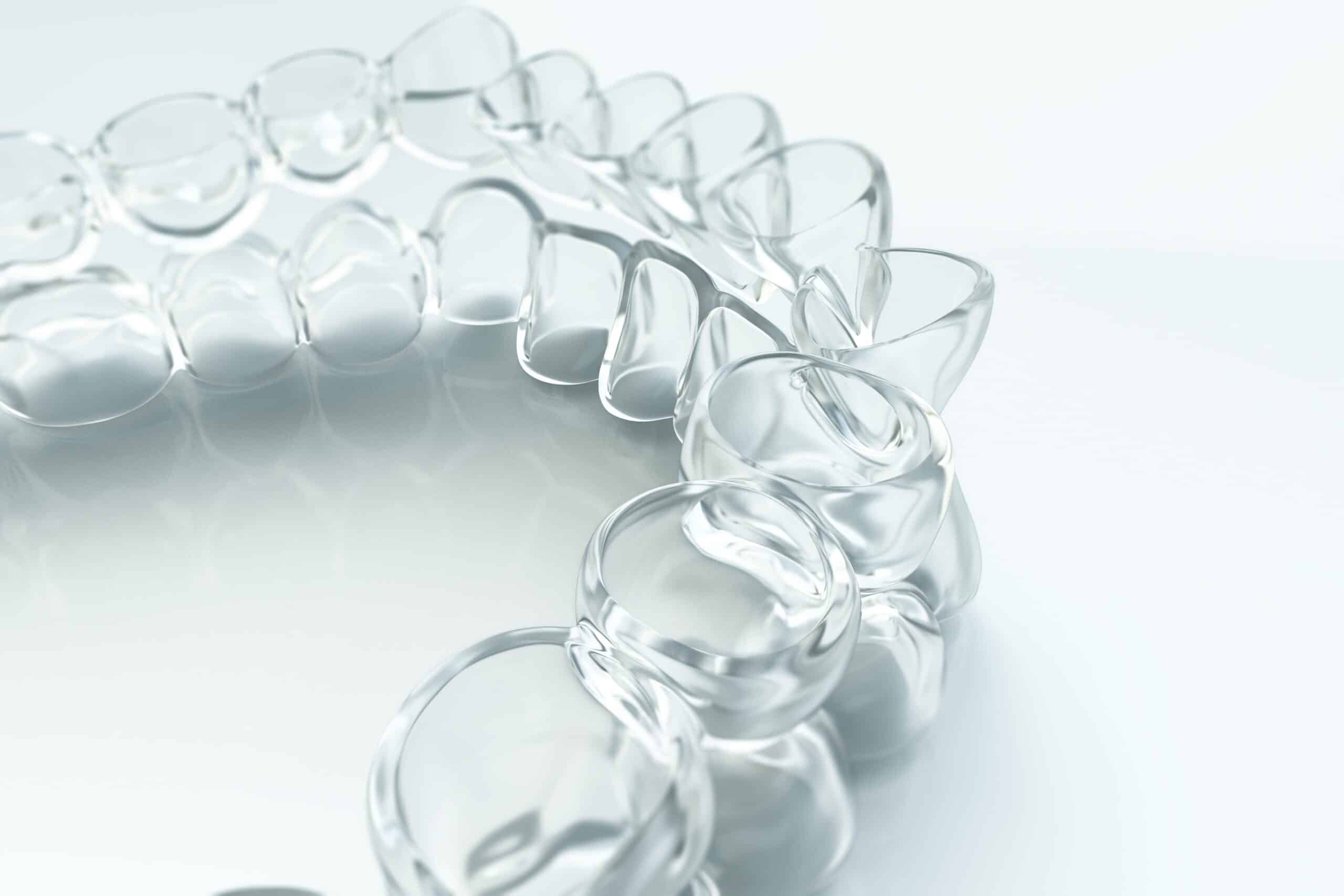 Transparent dental aligners are arranged in a circular pattern on a reflective surface, showcasing their sleek and modern design.